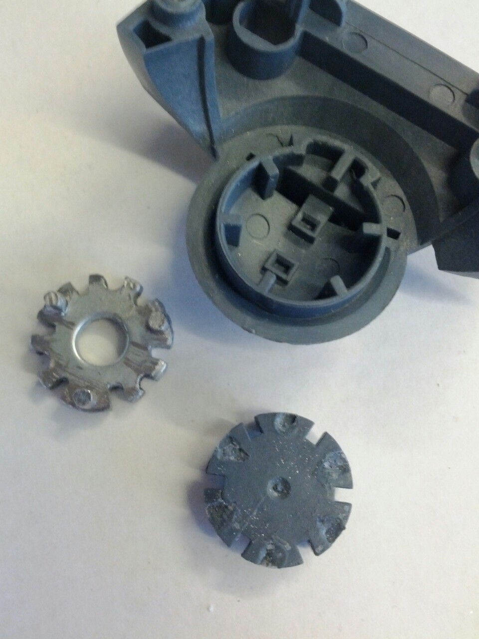 Broken plastic gear parts from a toy mechanism on a white surface