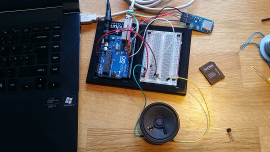 Arduino Uno with breadboard, SD card module and speaker beside a laptop