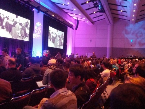 Large audience in a conference hall with stage screens at CHI 2014