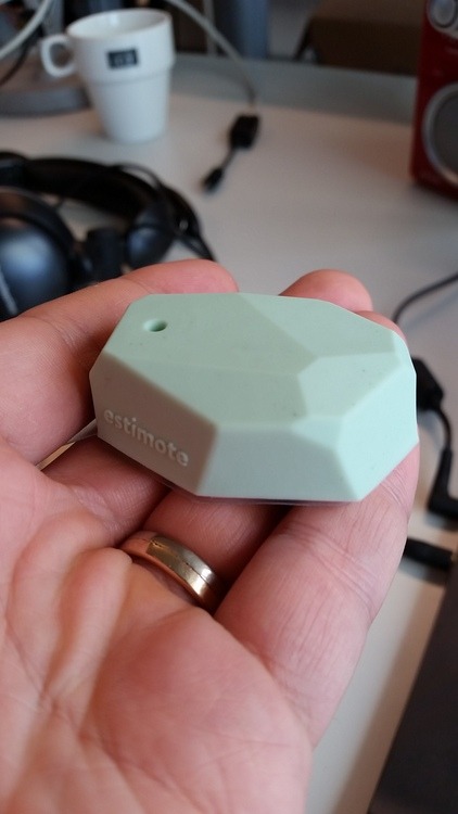 Hand holding a mint-green Estimote beacon